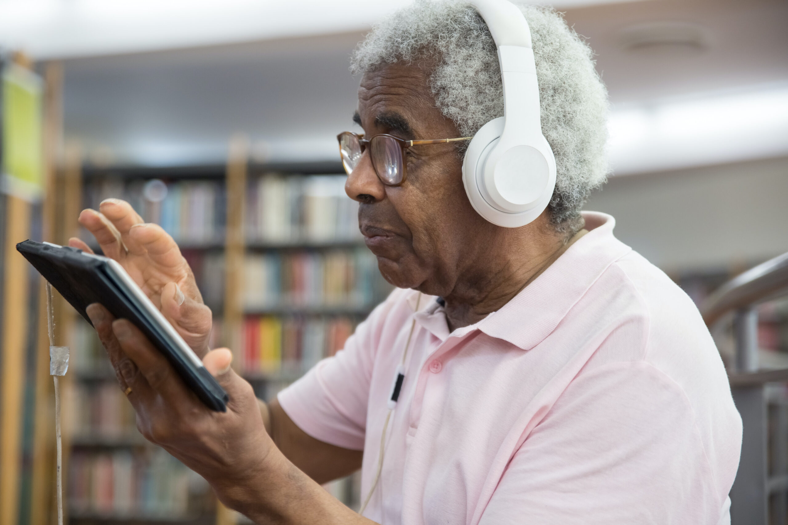 Homem mais velho usando um dispositivo digital e fones de ouvido